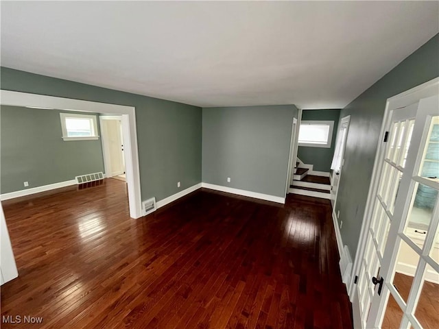 empty room with visible vents, stairway, baseboards, and hardwood / wood-style flooring