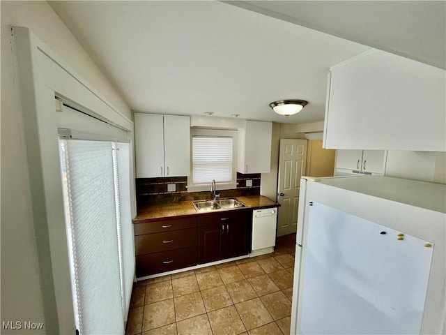 kitchen featuring white appliances, a sink, white cabinets, dark brown cabinets, and decorative backsplash