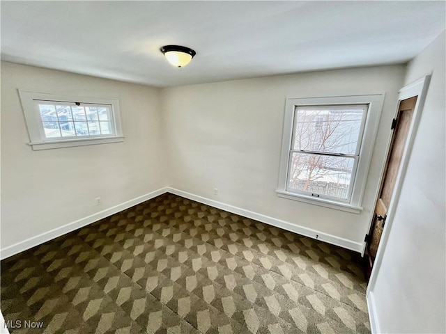 empty room with dark colored carpet and baseboards