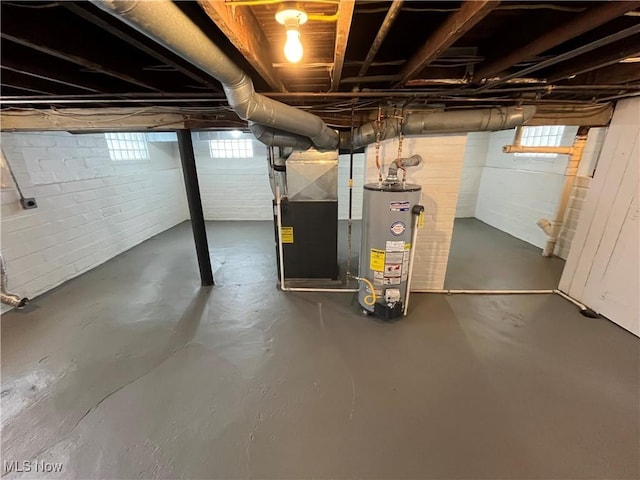 basement featuring gas water heater, a wealth of natural light, and heating unit