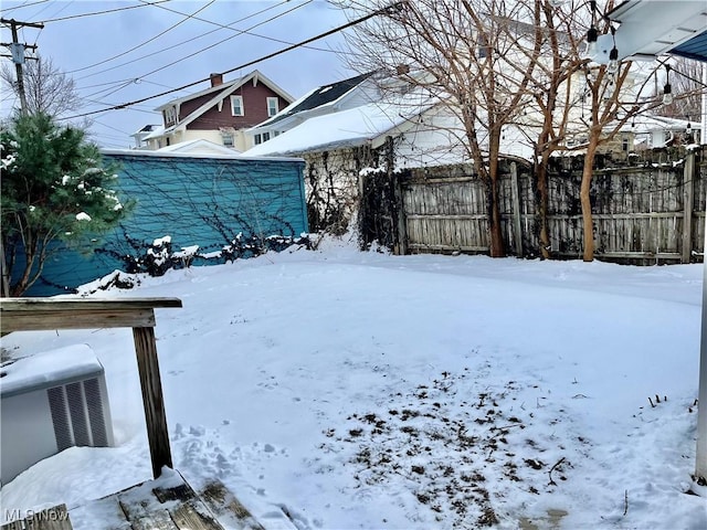 snowy yard featuring fence