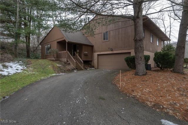 chalet / cabin featuring a garage, driveway, and roof with shingles