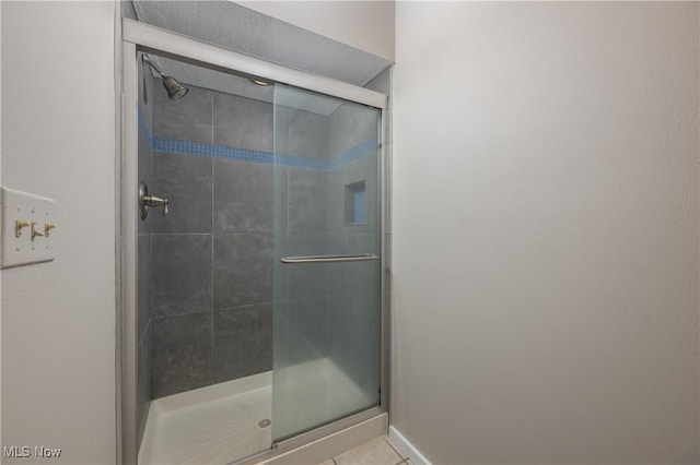 full bath with a shower stall and tile patterned floors