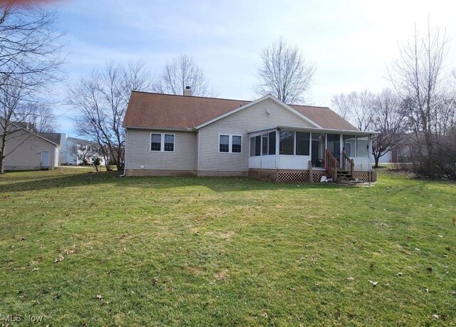 rear view of house featuring a sunroom, a chimney, a lawn, and roof with shingles