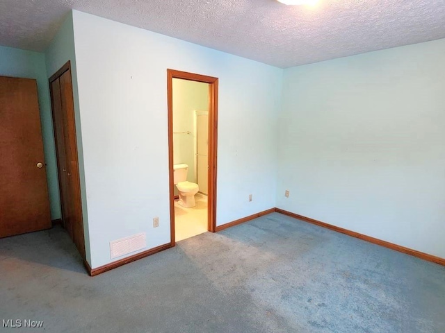 carpeted empty room with visible vents, a textured ceiling, and baseboards
