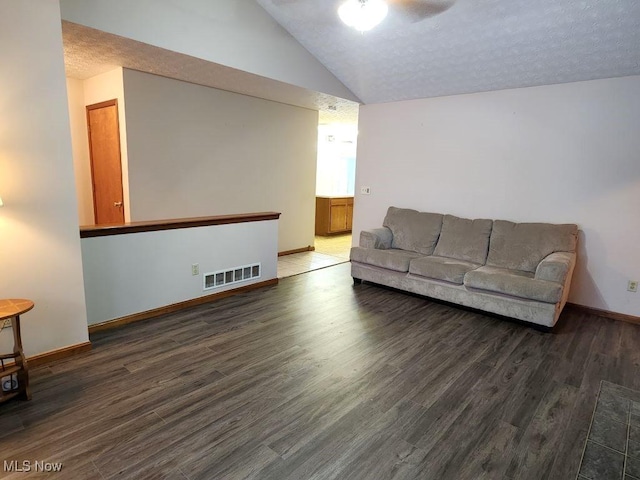 living area with lofted ceiling, a textured ceiling, wood finished floors, visible vents, and baseboards