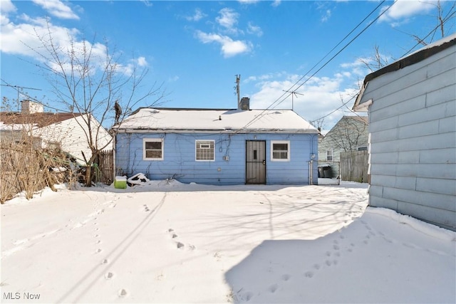 snow covered property with a chimney and fence