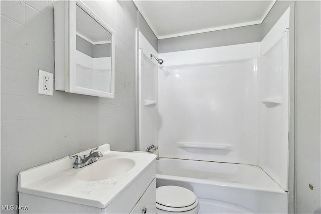 full bath with shower / washtub combination, tile walls, toilet, ornamental molding, and vanity