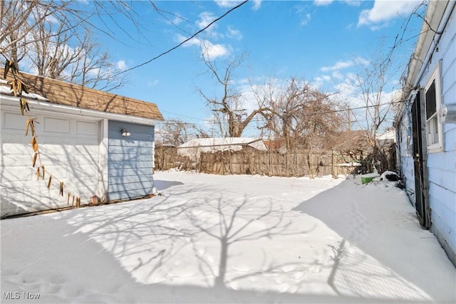 snowy yard featuring fence and an outdoor structure