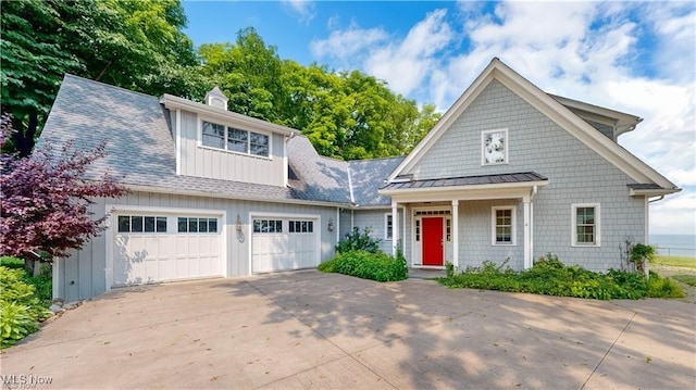 shingle-style home with a chimney, a shingled roof, concrete driveway, a standing seam roof, and metal roof