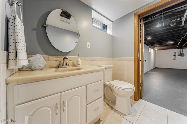 bathroom with toilet, tile patterned floors, tile walls, and vanity