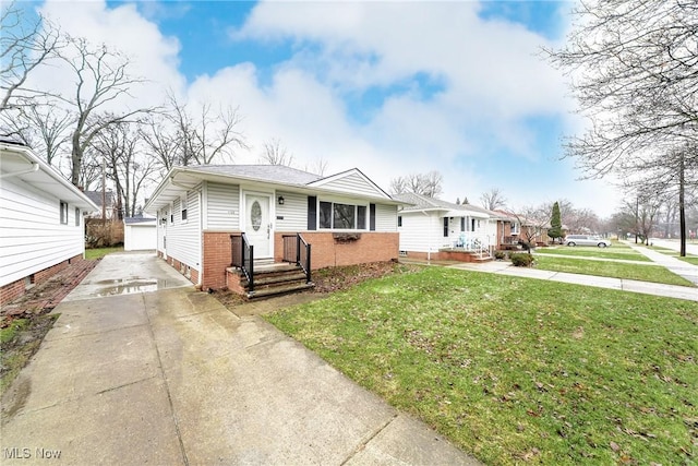 bungalow-style house featuring an outbuilding, driveway, a front lawn, and brick siding