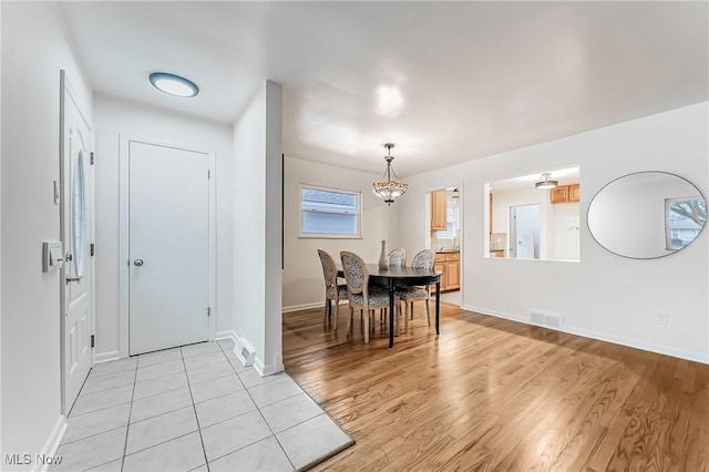 dining room with light wood finished floors, baseboards, and visible vents