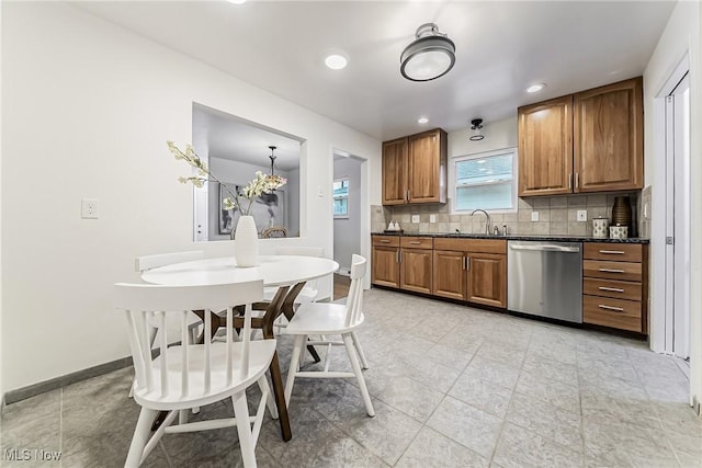 kitchen featuring baseboards, brown cabinets, dishwasher, tasteful backsplash, and dark countertops