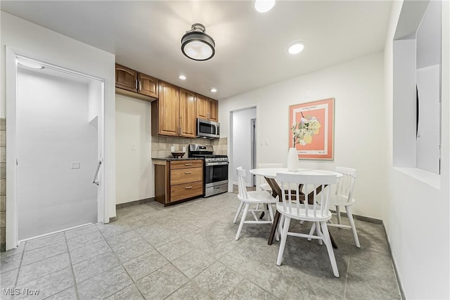 kitchen with tasteful backsplash, baseboards, brown cabinets, stainless steel appliances, and recessed lighting