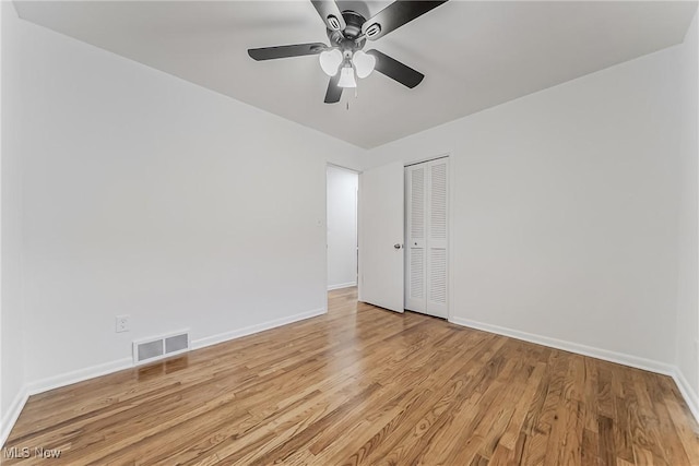 empty room with baseboards, a ceiling fan, visible vents, and light wood-style floors