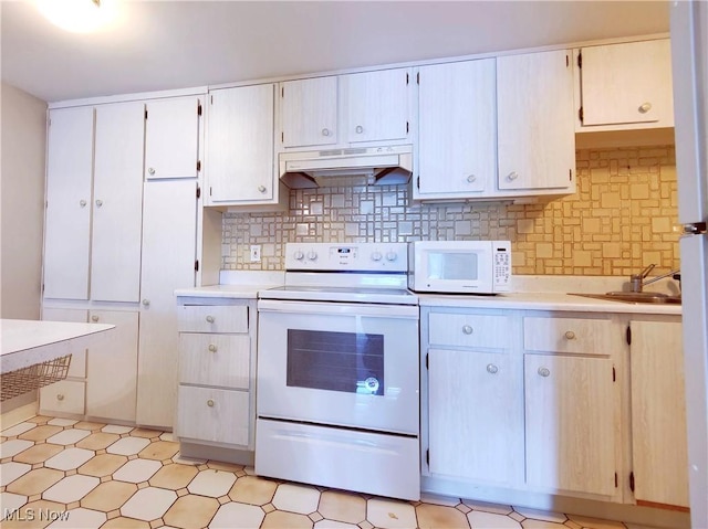 kitchen featuring light countertops, decorative backsplash, a sink, white appliances, and under cabinet range hood