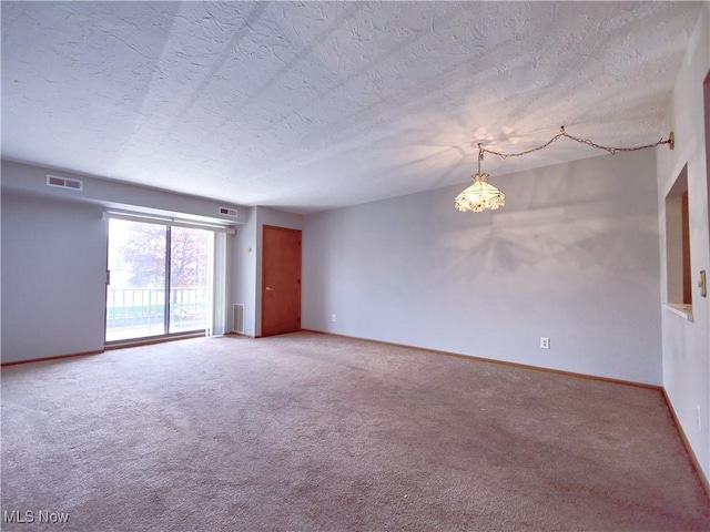 spare room with a textured ceiling, light carpet, visible vents, and baseboards