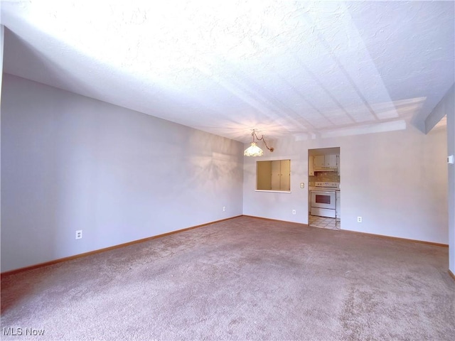 unfurnished living room featuring baseboards, a textured ceiling, a chandelier, and carpet flooring