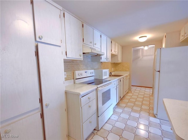 kitchen with light countertops, backsplash, a sink, white appliances, and under cabinet range hood