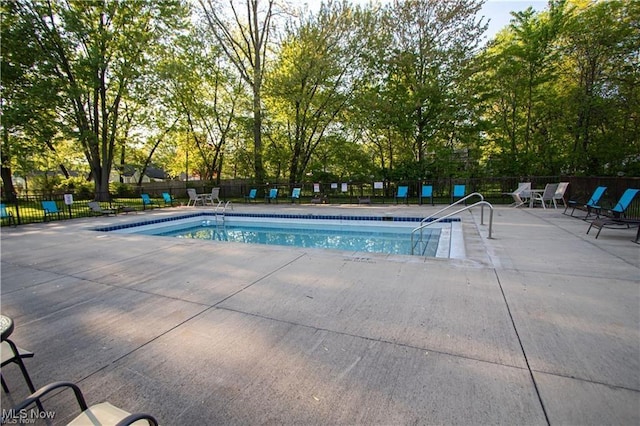 community pool with a patio area and fence