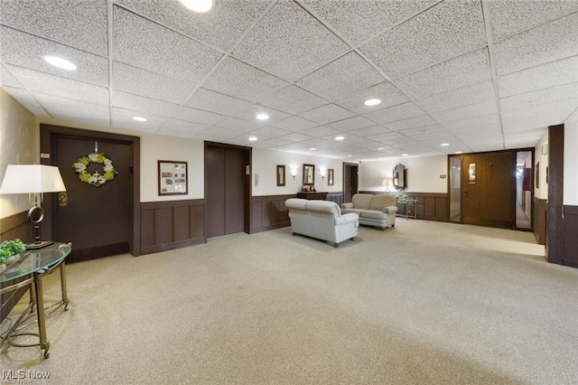 carpeted living room featuring recessed lighting, elevator, and wainscoting