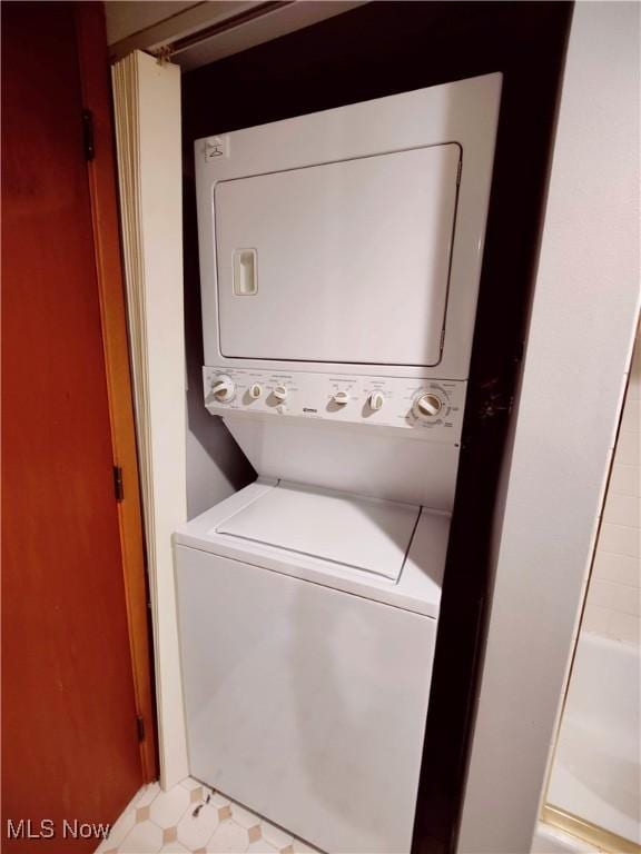 laundry area with stacked washer and dryer, laundry area, and light floors