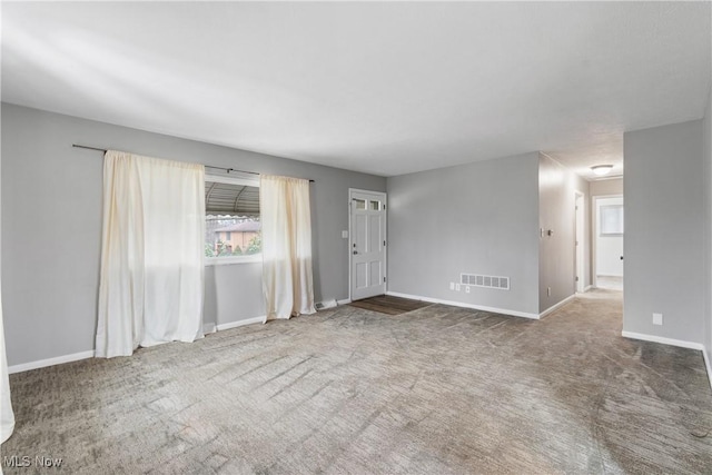 carpeted empty room featuring baseboards and visible vents