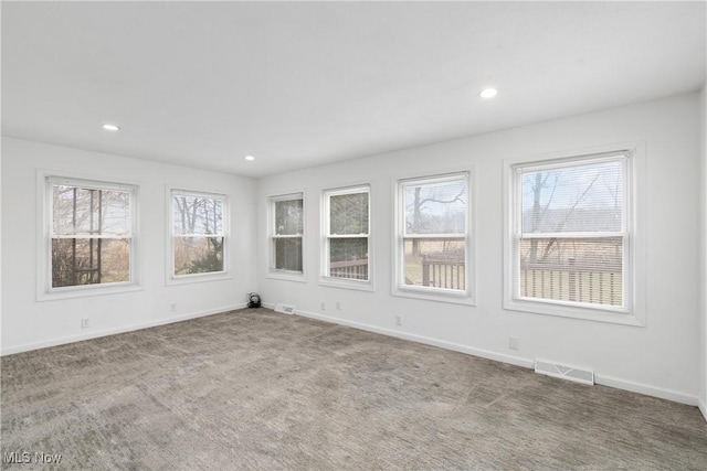 empty room with carpet floors, recessed lighting, visible vents, and baseboards