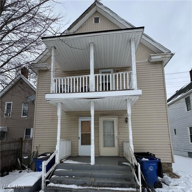 view of front of house featuring a porch, fence, and a balcony