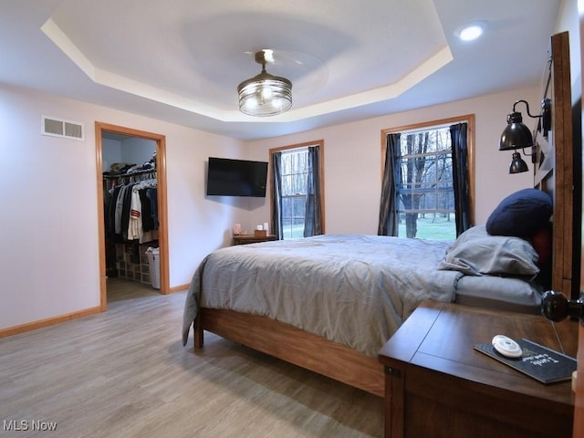 3945 Wheeler Creek Rd, Geneva, OH 44041 - bedroom with visible vents, baseboards, a raised ceiling, light wood-type flooring, and a walk in closet