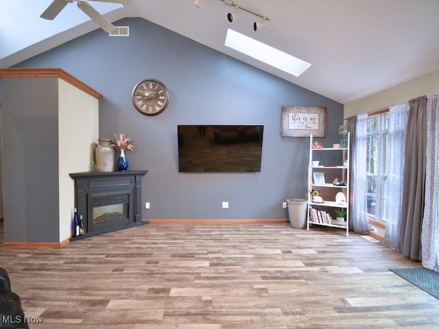 3945 Wheeler Creek Rd, Geneva, OH 44041 - living room featuring visible vents, ceiling fan, lofted ceiling with skylight, wood finished floors, and a glass covered fireplace