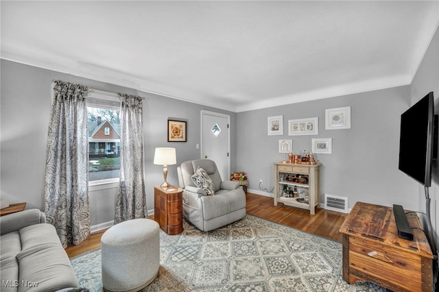 living room with baseboards, visible vents, and wood finished floors