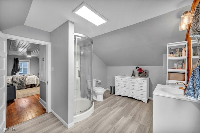 full bathroom with a stall shower, connected bathroom, vaulted ceiling, and wood finished floors