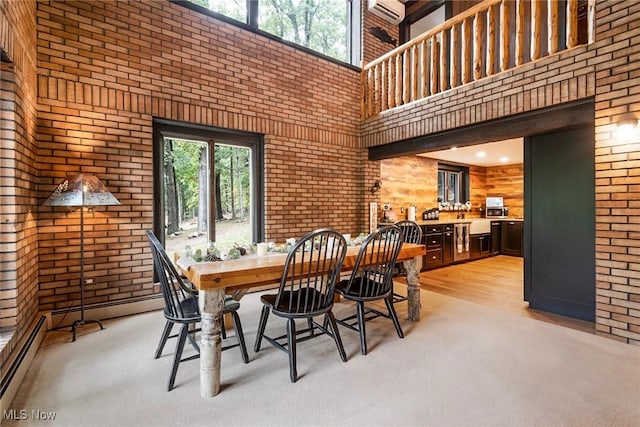 dining room featuring a baseboard heating unit, brick wall, plenty of natural light, and a towering ceiling