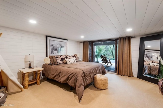 bedroom with light carpet, wooden walls, recessed lighting, and access to exterior