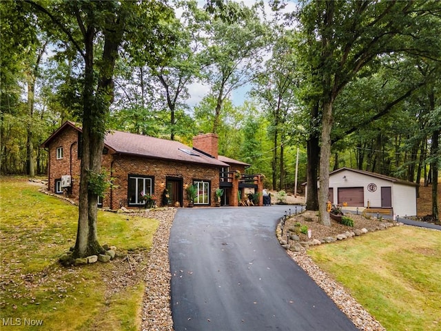 view of front of home featuring a garage, a chimney, an outbuilding, a front lawn, and brick siding