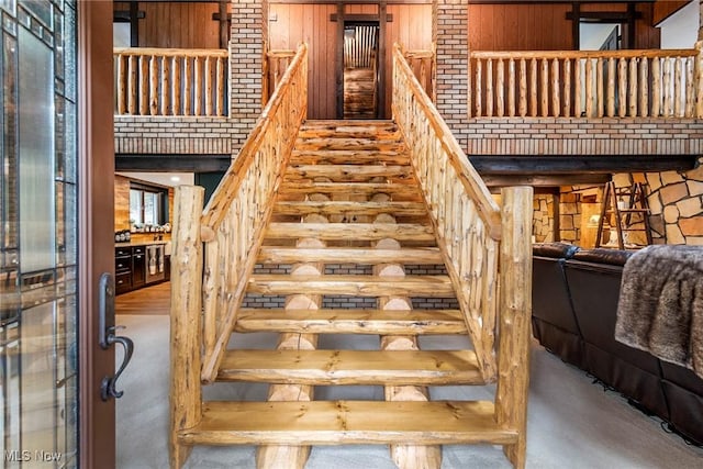 stairs featuring a towering ceiling and wooden walls