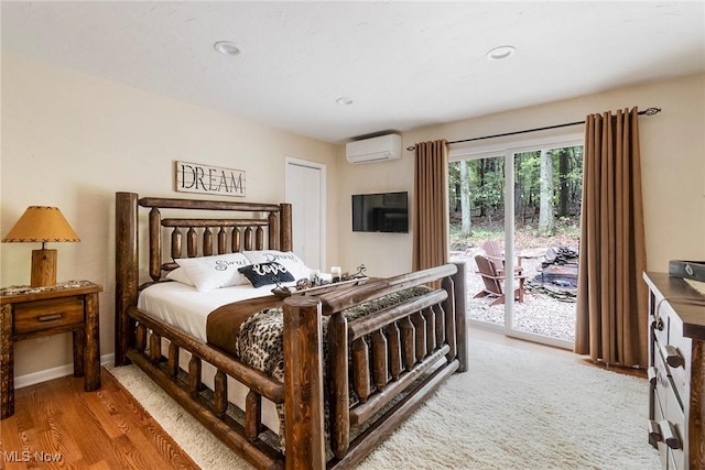 bedroom featuring access to exterior, recessed lighting, light wood-style floors, an AC wall unit, and baseboards