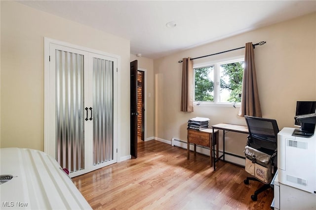 home office with baseboards, a baseboard heating unit, and light wood-style floors