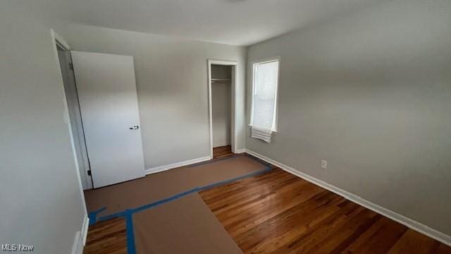 unfurnished bedroom with a closet, baseboards, and wood finished floors