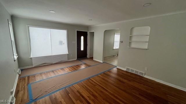 entrance foyer featuring baseboards, visible vents, arched walkways, and wood finished floors