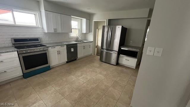 kitchen featuring appliances with stainless steel finishes, a sink, white cabinetry, and tasteful backsplash