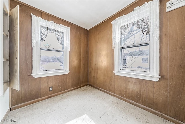 empty room with wood walls, tile patterned floors, and baseboards