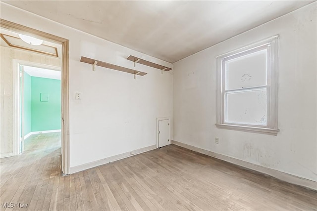 unfurnished room with light wood-type flooring and baseboards