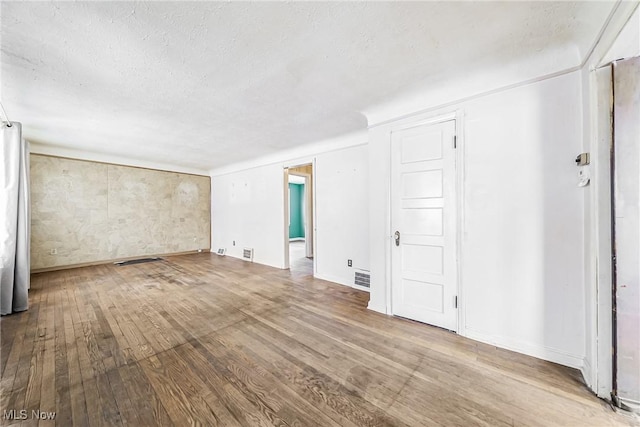 interior space featuring a textured ceiling, hardwood / wood-style floors, and visible vents