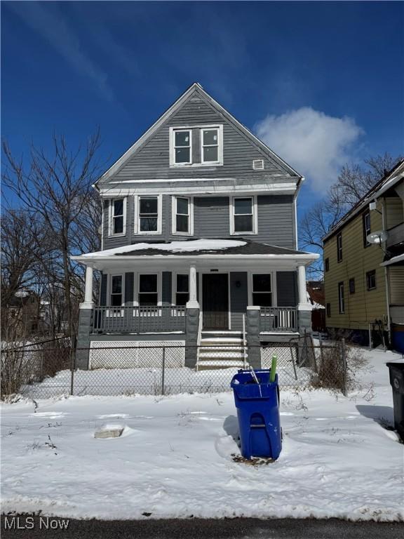 american foursquare style home featuring covered porch and fence