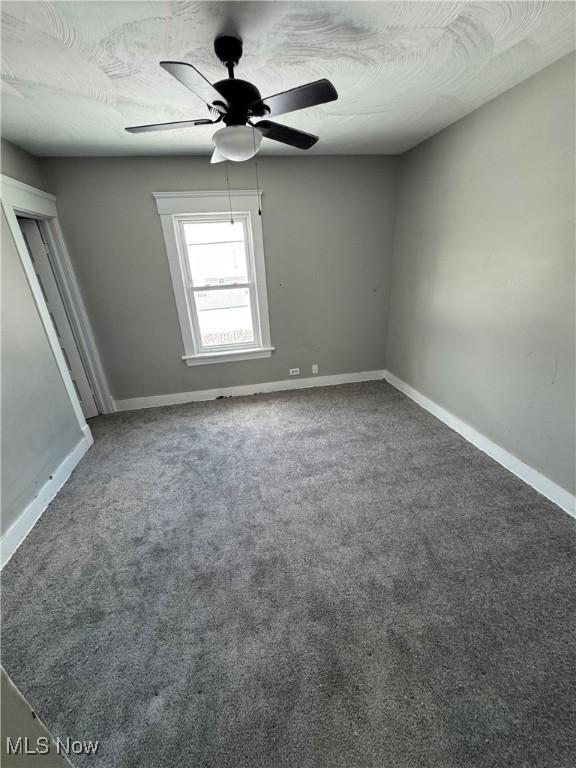 empty room featuring carpet floors, ceiling fan, a textured ceiling, and baseboards