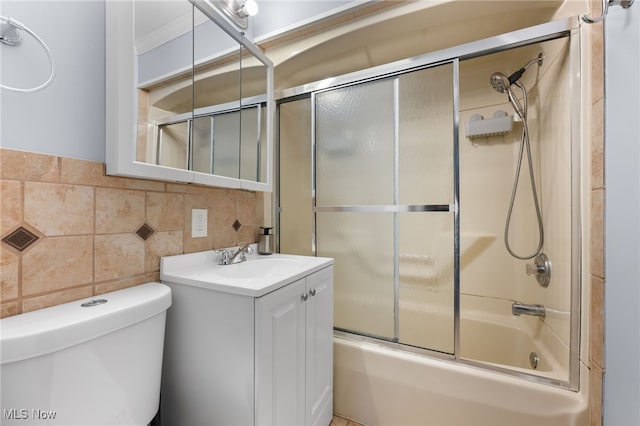 bathroom featuring enclosed tub / shower combo, toilet, vanity, tile walls, and crown molding