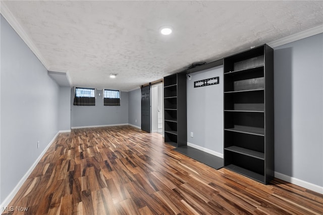 below grade area featuring a barn door, baseboards, a textured ceiling, and wood finished floors